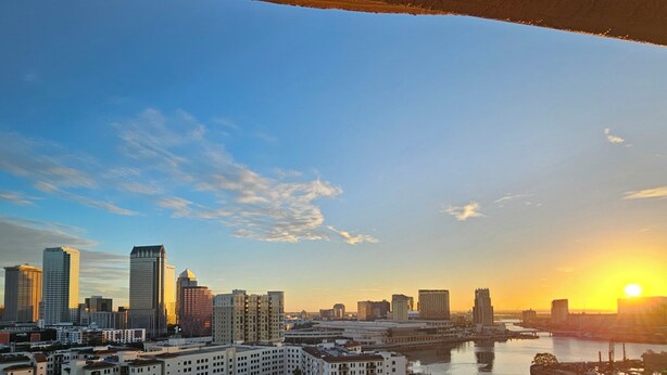A cityscape with a river, buildings, and a bridge during sunset. - Luxury 2-bedroom waterfront condo with parking, in sunny South Tampa (Tampa)