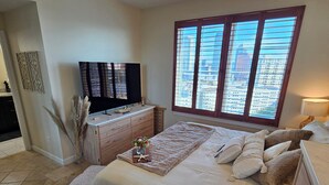 A bedroom with a large bed, a TV, a window with blinds, and a dresser. - Luxury 2-bedroom waterfront condo with parking, in sunny South Tampa (Tampa)