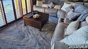 A living room with a sectional sofa, a coffee table, and a large window with blinds. - Luxury 2-bedroom waterfront condo with parking, in sunny South Tampa (Tampa)