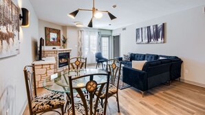 Ein modernes Wohnzimmer mit Kamin, Esstisch mit Stühlen, einer Couch und Kunstwerken an den Wänden.