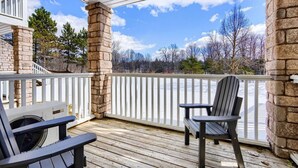 Eine überdachte Terrasse mit zwei Adirondack-Stühlen, einer Steinpfeiler und Blick auf eine verschneite Landschaft.