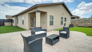 Ein modernes Haus mit Terrasse, ausgestattet mit Korbmöbeln und einer Steinwand.
