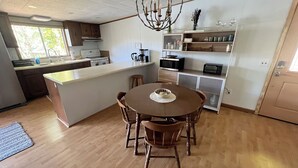 Een moderne keuken met een centraal eiland, houten stoelen en inbouwapparatuur.