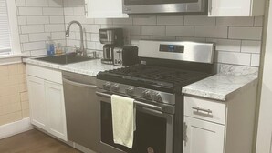 Une cuisine avec des meubles blancs, une cuisinière en acier inoxydable, un four à micro-ondes et une machine à café.