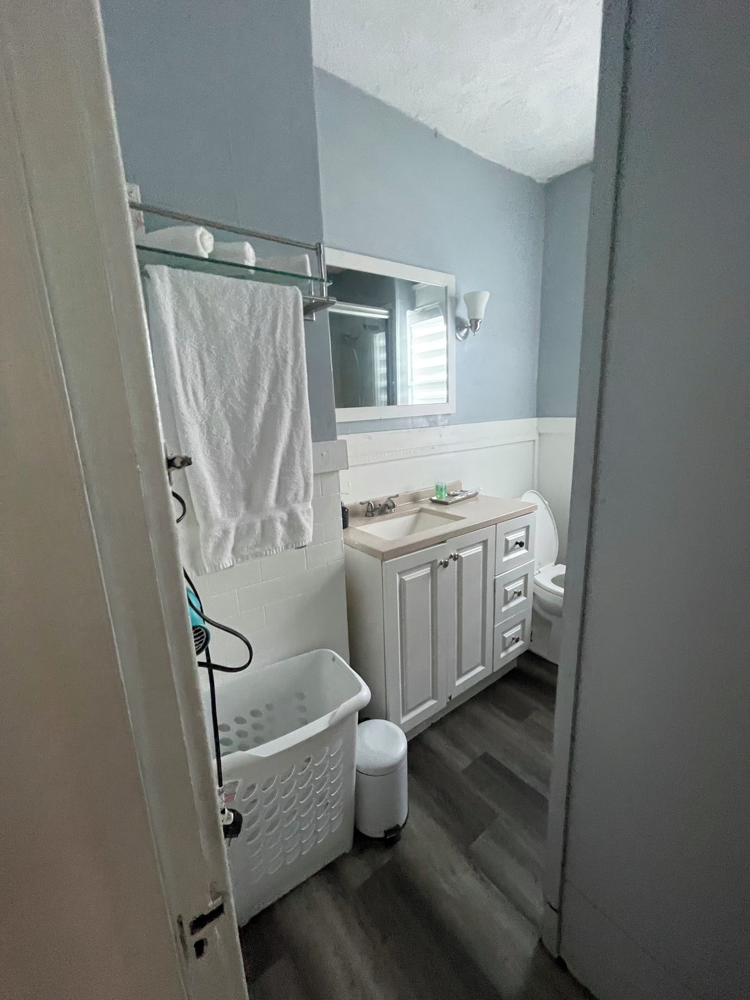 A bathroom with a shower, a sink, a toilet, and a mirror.