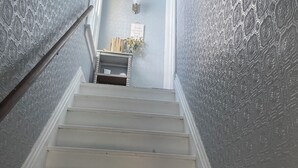 A staircase with a patterned wall and a small shelf with books and a vase.
