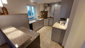 A modern kitchen with granite countertops, stainless steel appliances, and a window providing natural light.