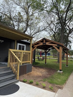 A wooden deck with a railing, a covered patio area, and a small garden with young plants.