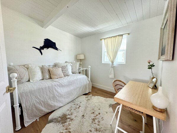 Un dormitorio con cama, mesita de noche, lámpara, silla y un adorno en la pared.