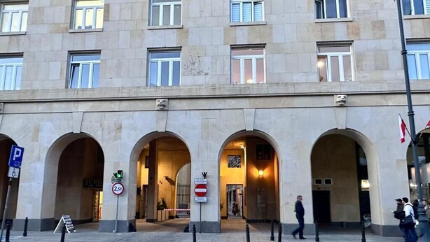 Un edificio con varias entradas arqueadas, un paso de peatones y un cartel de prohibido el acceso.