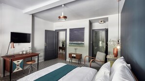 Habitación de hotel con cama, escritorio, silla y televisor.