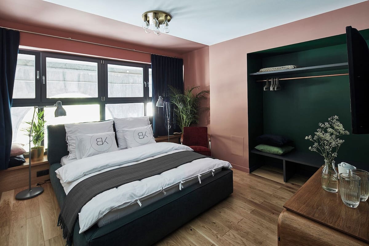 A modern bedroom with a bed, bedside tables, a desk, a wardrobe, and a window.
