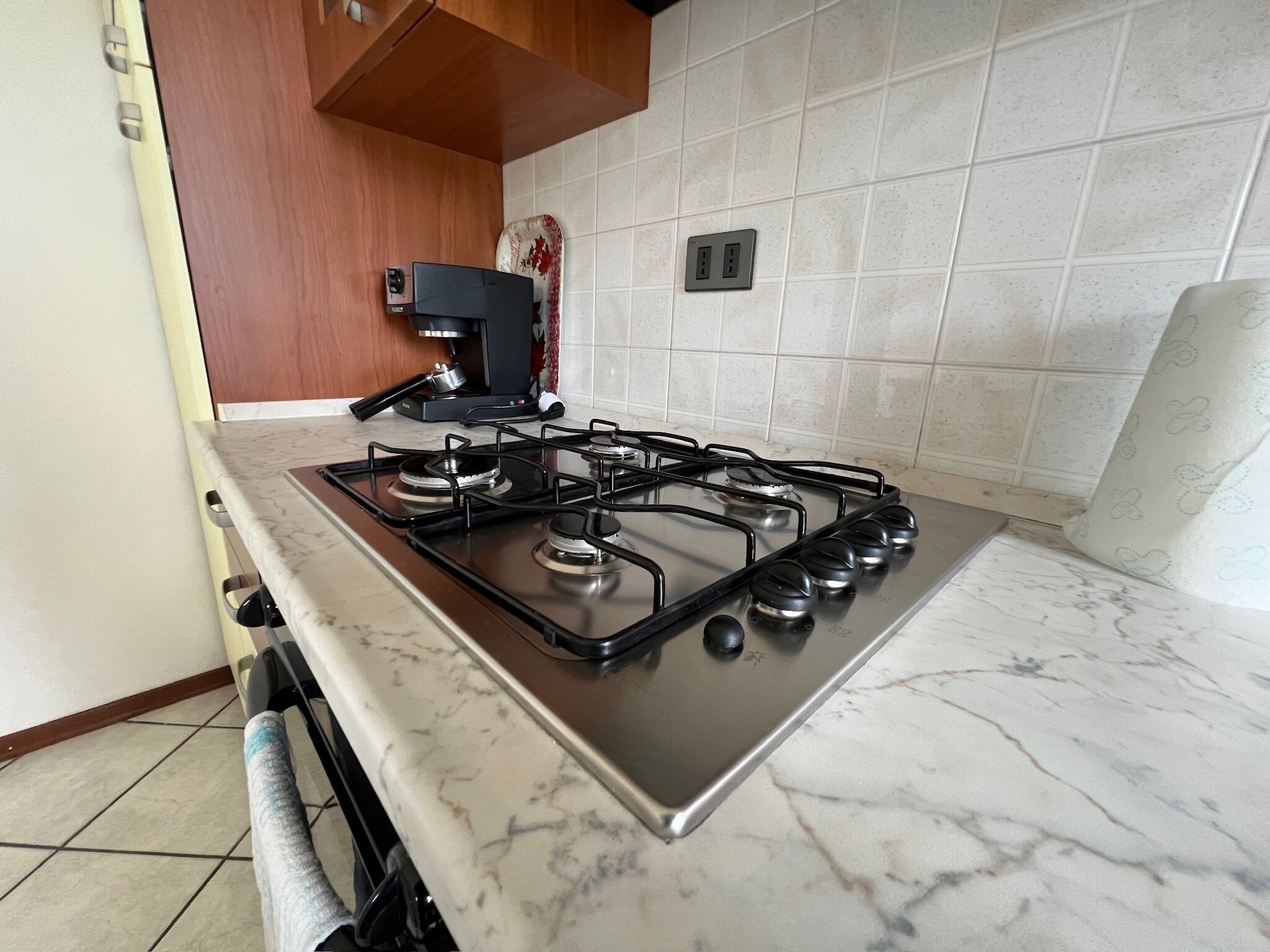 A kitchen with a gas stove, a coffee maker, and a tiled backsplash.