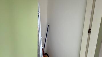 Un passadís estret amb una porta blanca a la dreta i una paret verda a l'esquerra.