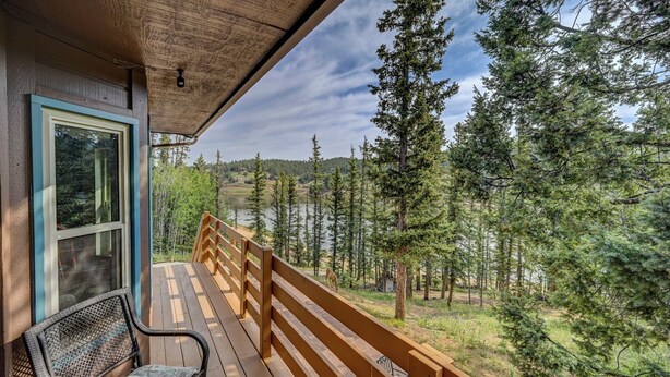 Una terraza de madera con un banco y un ventanal de vidrio que da a una habitación.