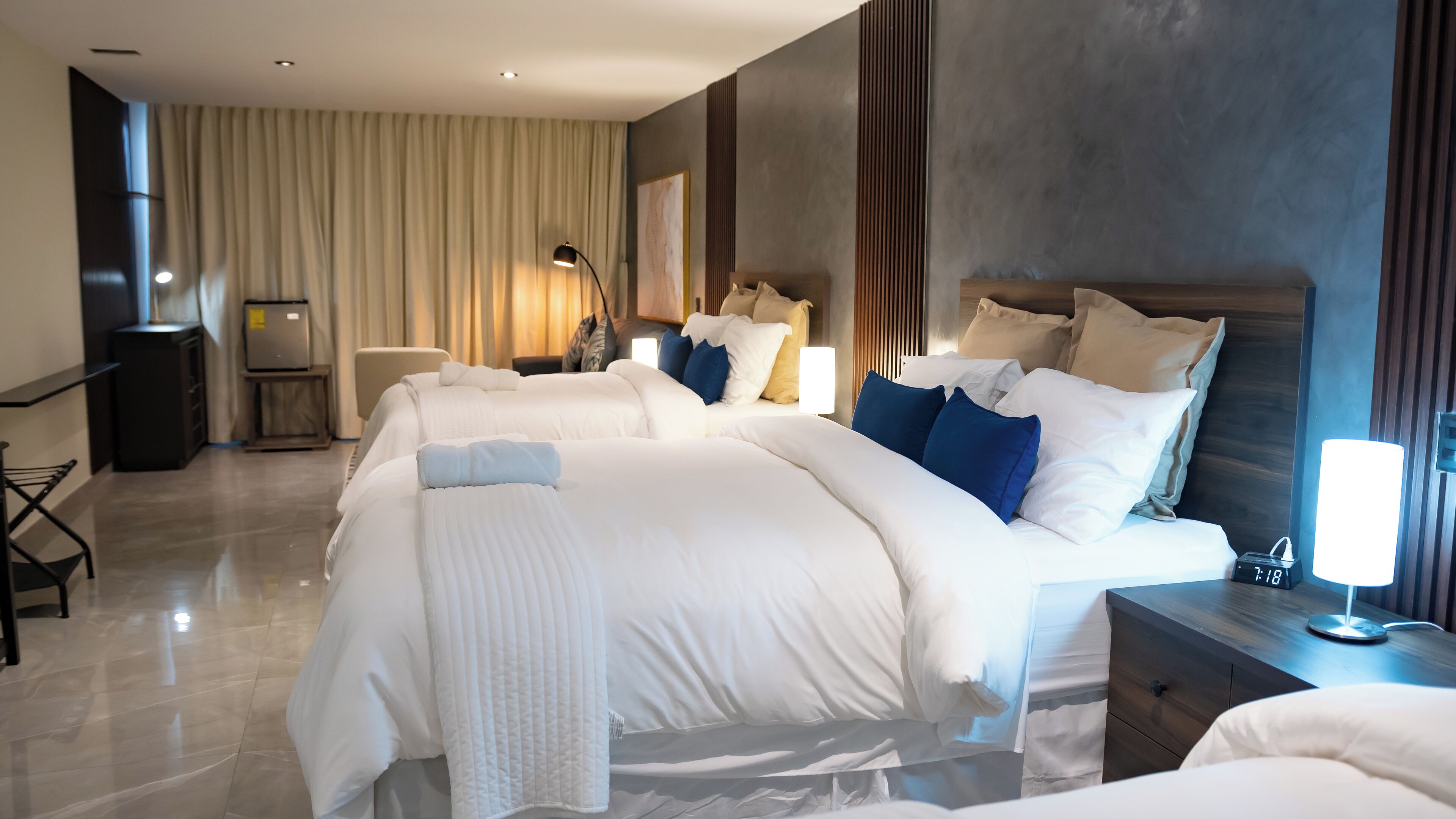 Una habitación de hotel con una cama grande, mesitas de noche, un escritorio y un armario.