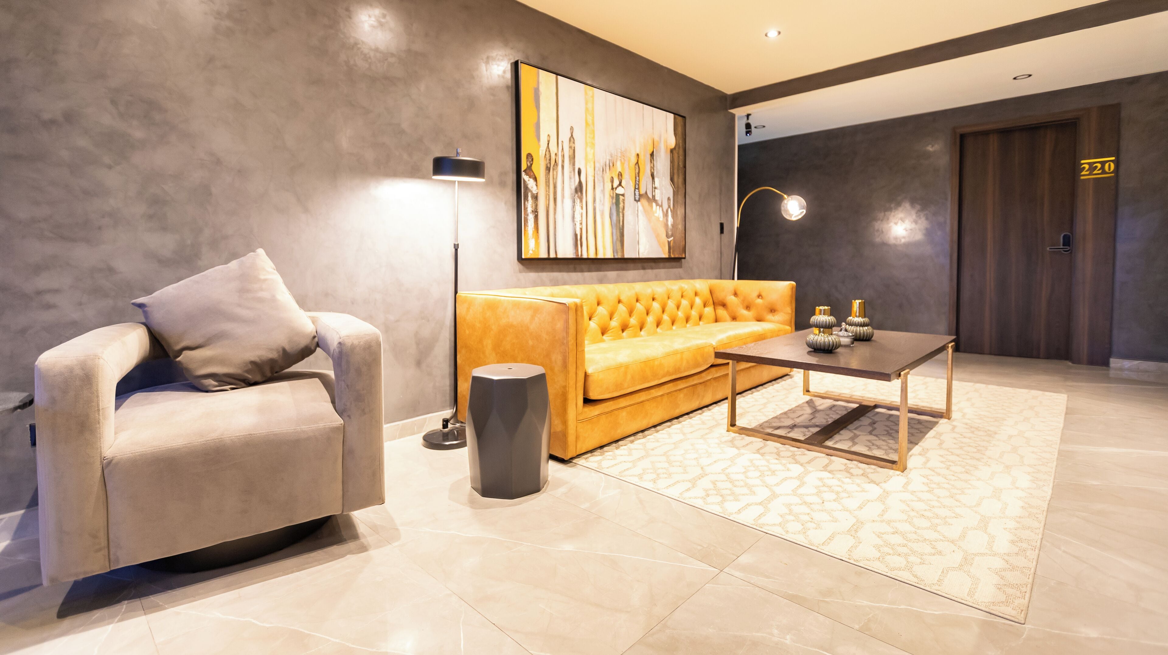 A modern lobby with a beige sofa, a coffee table, a floor lamp, and a painting on the wall.