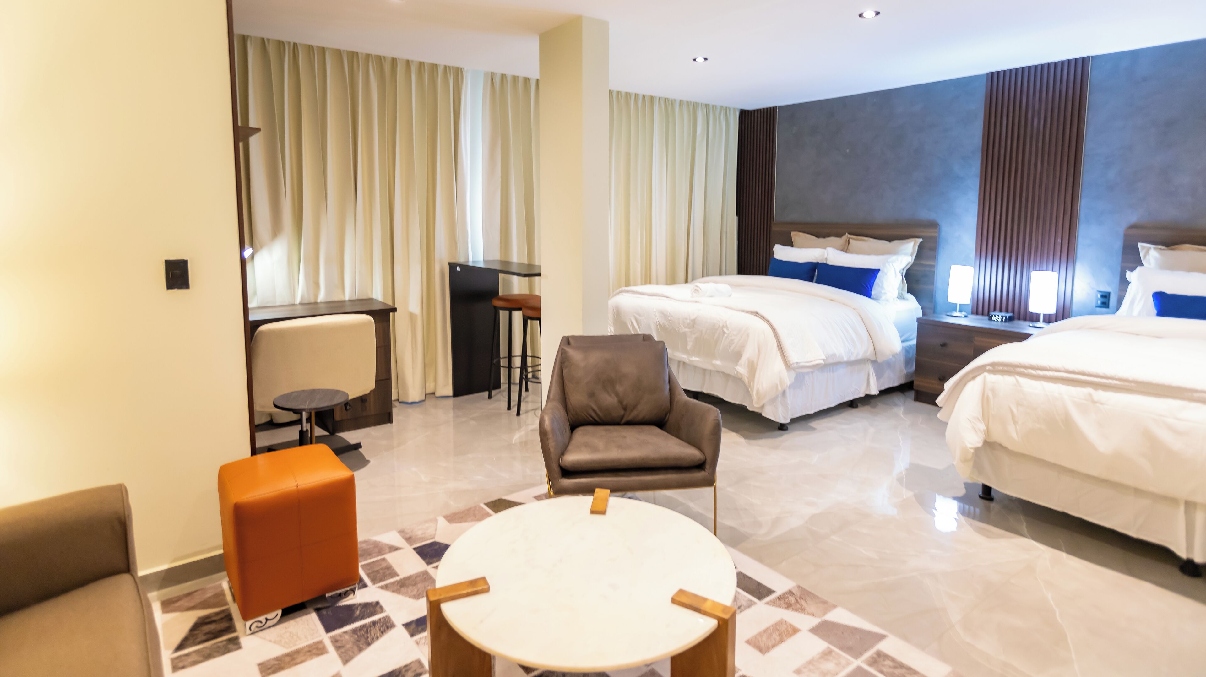 Une chambre d’hôtel avec deux lits, un bureau, une chaise et une petite table.