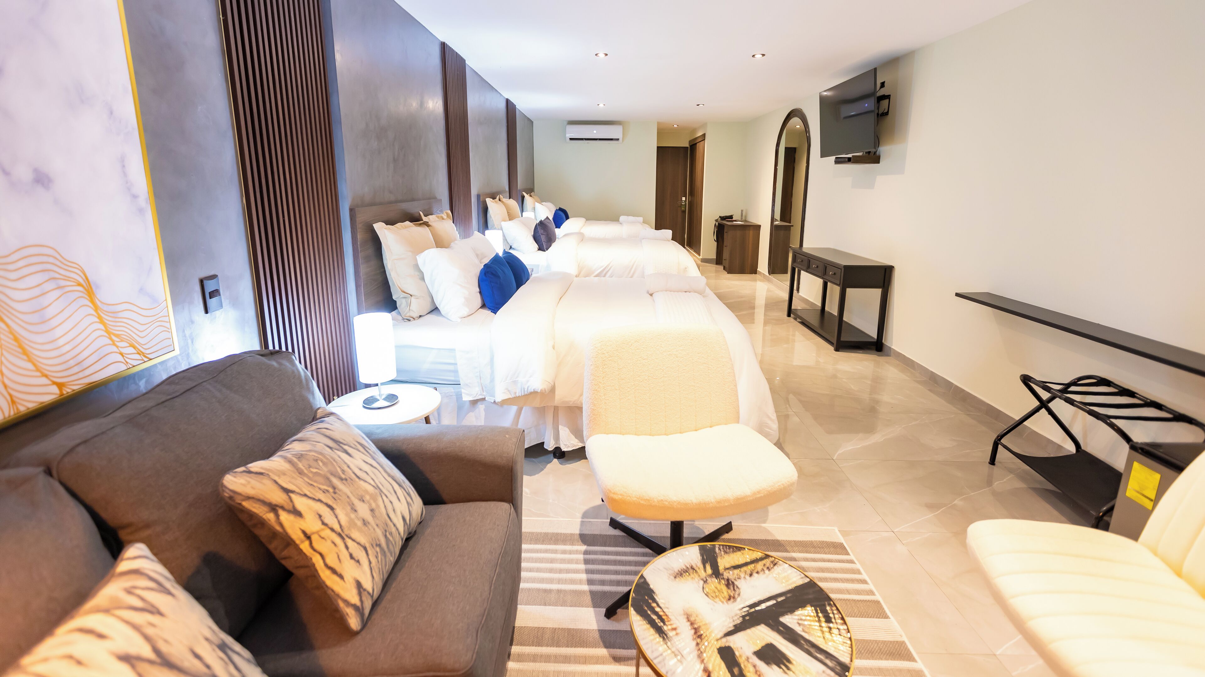 Ein modernes Hotelzimmer mit einer Couch, einer Massageliege und einem an der Wand befestigten Fernseher.