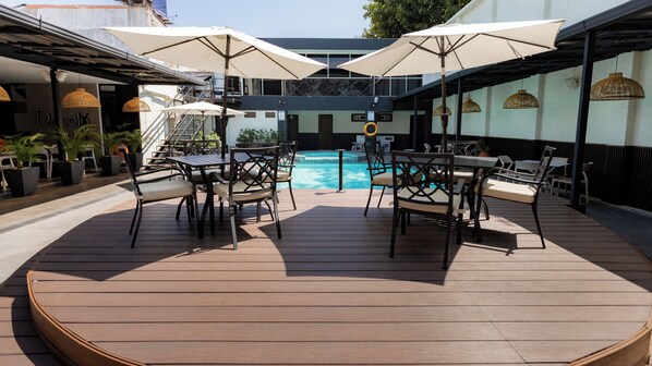 Un espace aménagé au bord de la piscine, avec des sièges et des parasols.