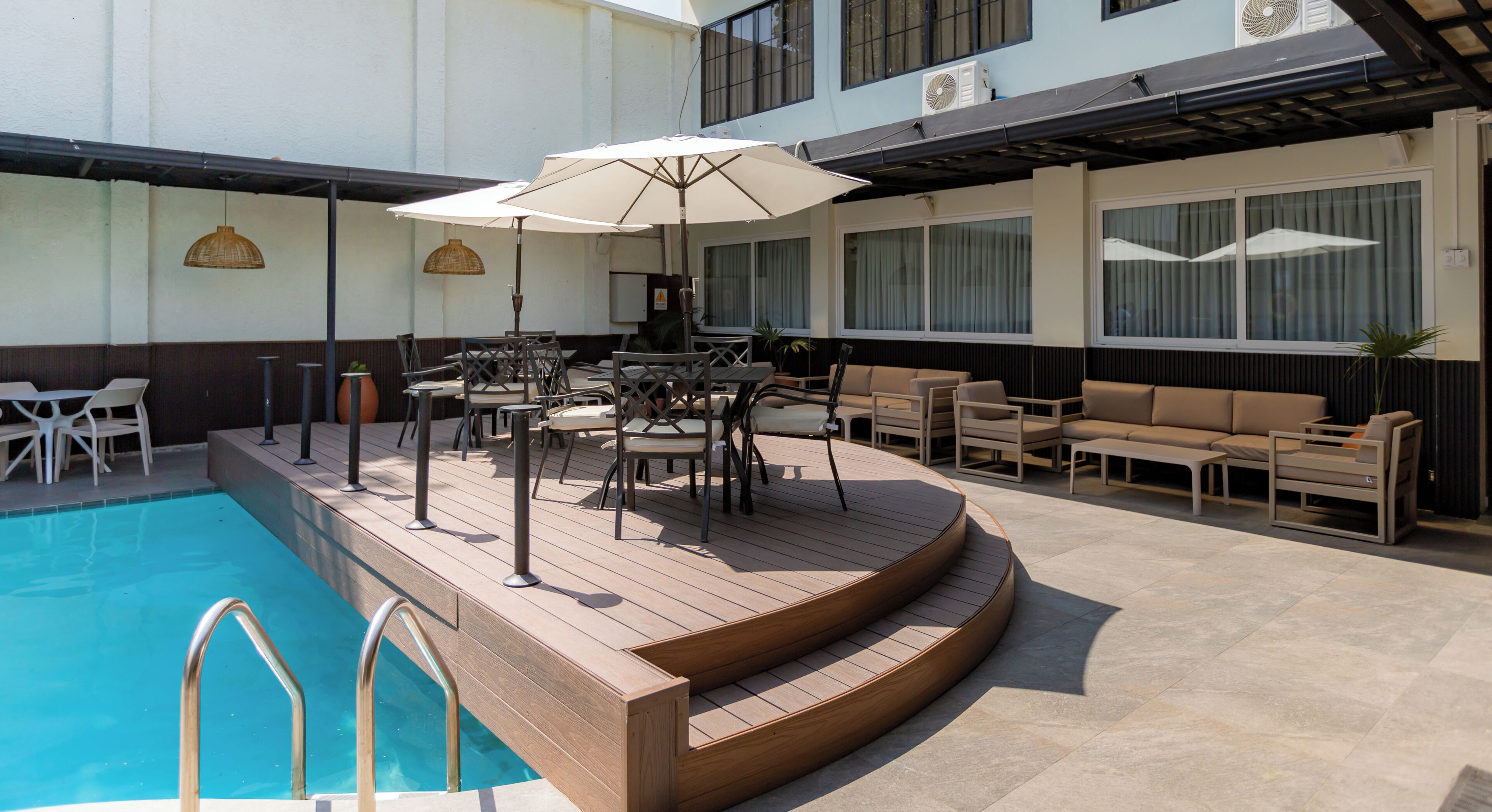 Ein Poolbereich mit Holzterrasse, Sitzgelegenheiten im Freien und einem Schwimmbecken.
