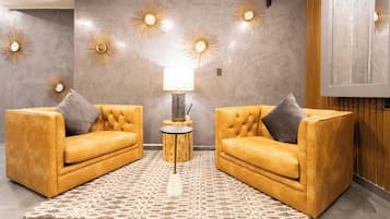 Una sala de estar moderna con dos sofás de cuero amarillos, un tapete estampado y apliques decorativos.