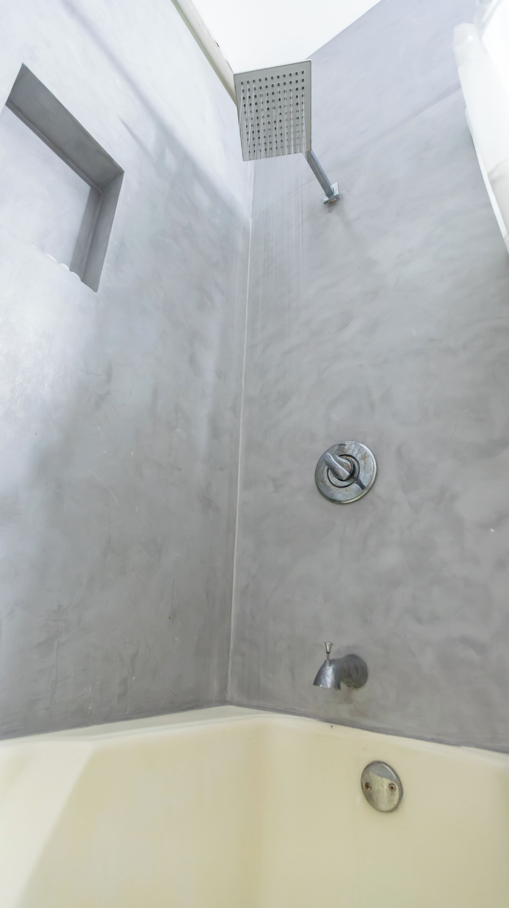 Una esquina del baño con ducha, bañera y un lavamanos pequeño.