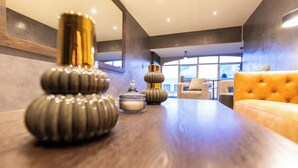 Ein modernes Interieur mit einem Holztisch, der dekorative Vasen, ein Sofa und einen Blick ins Freie durch große Fenster zeigt.