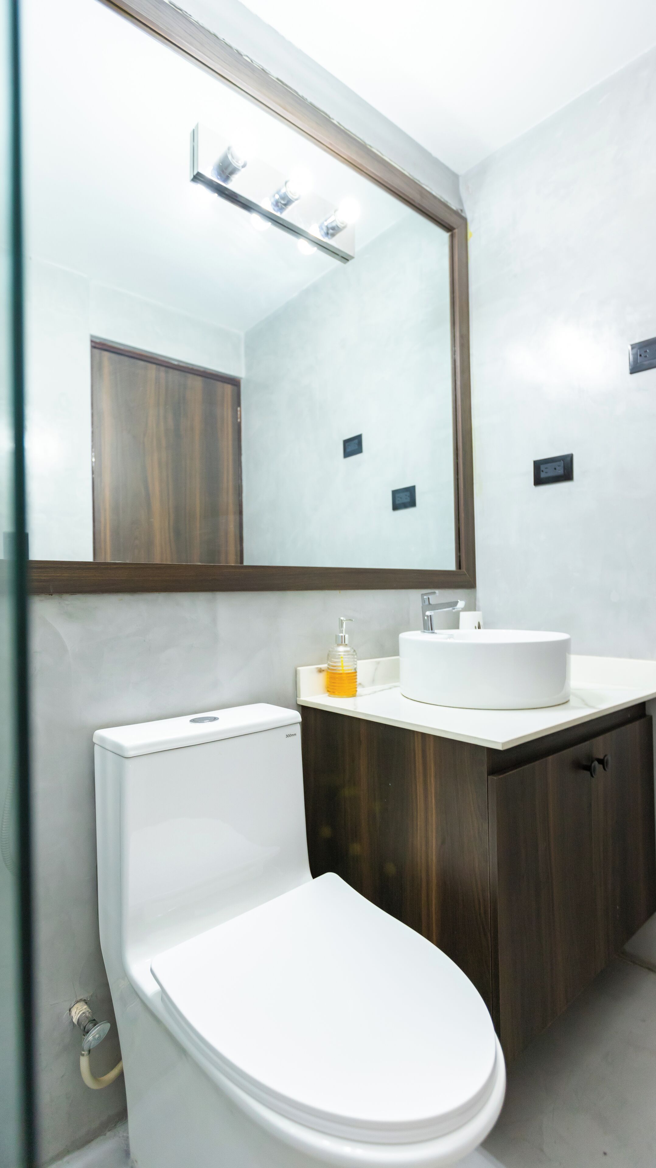 Un baño moderno con inodoro, lavabo y espejo.
