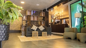 Eine moderne Lobby mit einem dunkelgrauen Sofa, zwei goldenen Beistelltischen und einem Empfangstresen mit Computern.