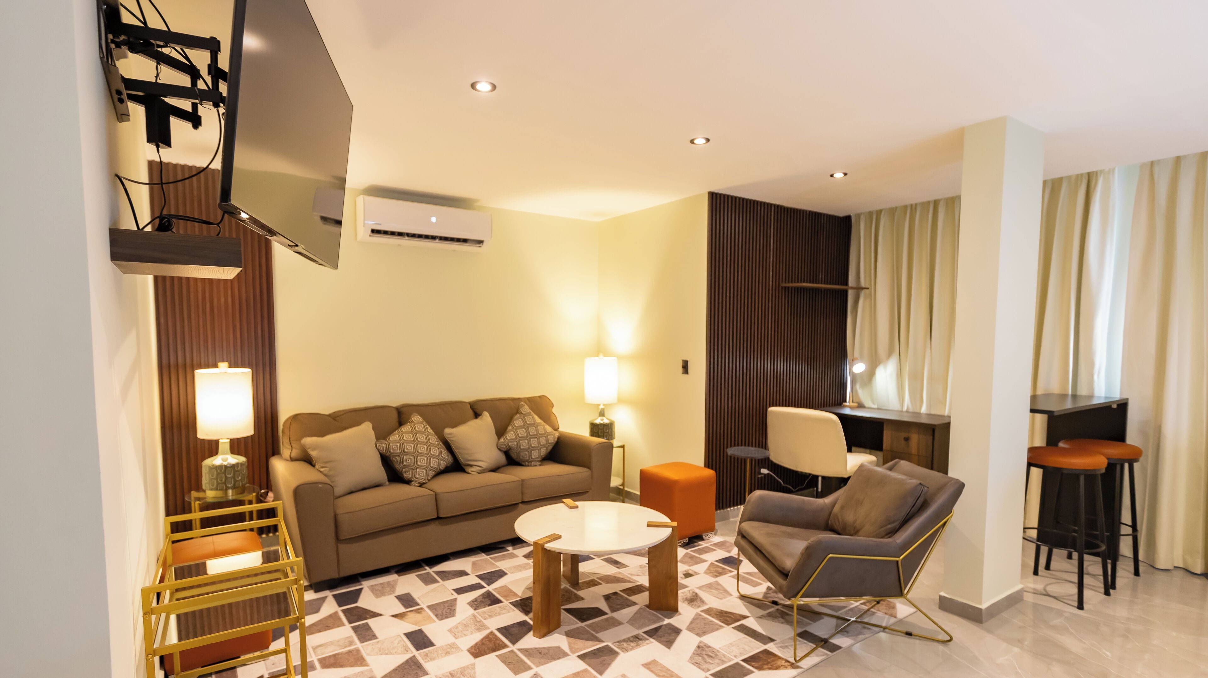A modern living room with a sofa, armchair, coffee table, and a TV mounted on the wall.