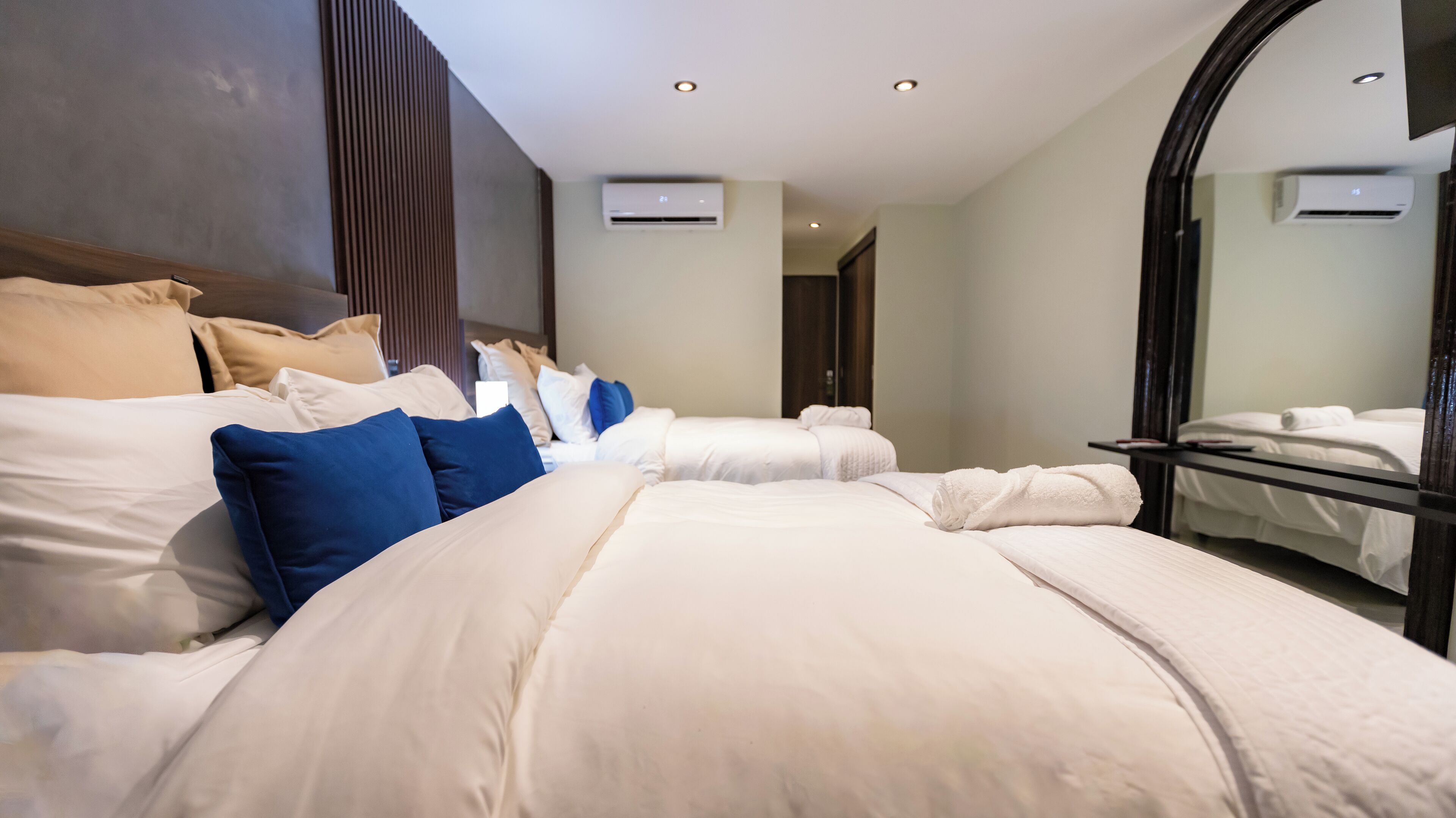 A modern hotel room with a large bed, a bedside table, and a mirror.