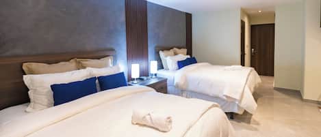 Una habitación de hotel con dos camas, una mesita de noche y una lámpara de pared.