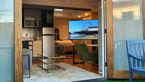 A compact living space with a kitchenette, a dining area with a TV displaying a Ferris wheel, and a small seating area with a chair. - Indoor and Outdoor Living (Los Angeles)