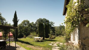 A garden with a table and chairs, a stone pathway, and a building with ivy. - L'Ange : Entre monts et vallées House with billiard table and fiber optics (Retournac)