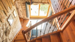 A wooden staircase with a metal railing leading to a room with a stone wall and a wooden door. - L'Ange : Entre monts et vallées House with billiard table and fiber optics (Retournac)