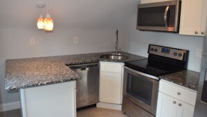 A compact kitchen with a stainless steel dishwasher, oven, and microwave.