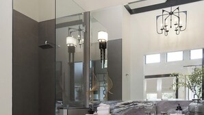 Une salle de bain moderne avec une douche à l’italienne en verre, un grand miroir et un plan de toilette en marbre.