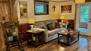 A cozy living room with wooden flooring, a rocking chair, a sofa, and a coffee table.