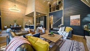 A spacious living area with a high ceiling, a dining area, and a kitchen. - A Point in Time: Sleeps 12-16 | Fire Pit | Hot Tub (Broken Bow)