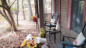 A porch with a wooden fence, two rocking chairs, and a hanging flower basket. - Charming 2-bedroom B&B in Honey Brook with WiFi, fitness room 
bed and breakfast (Honey Brook)