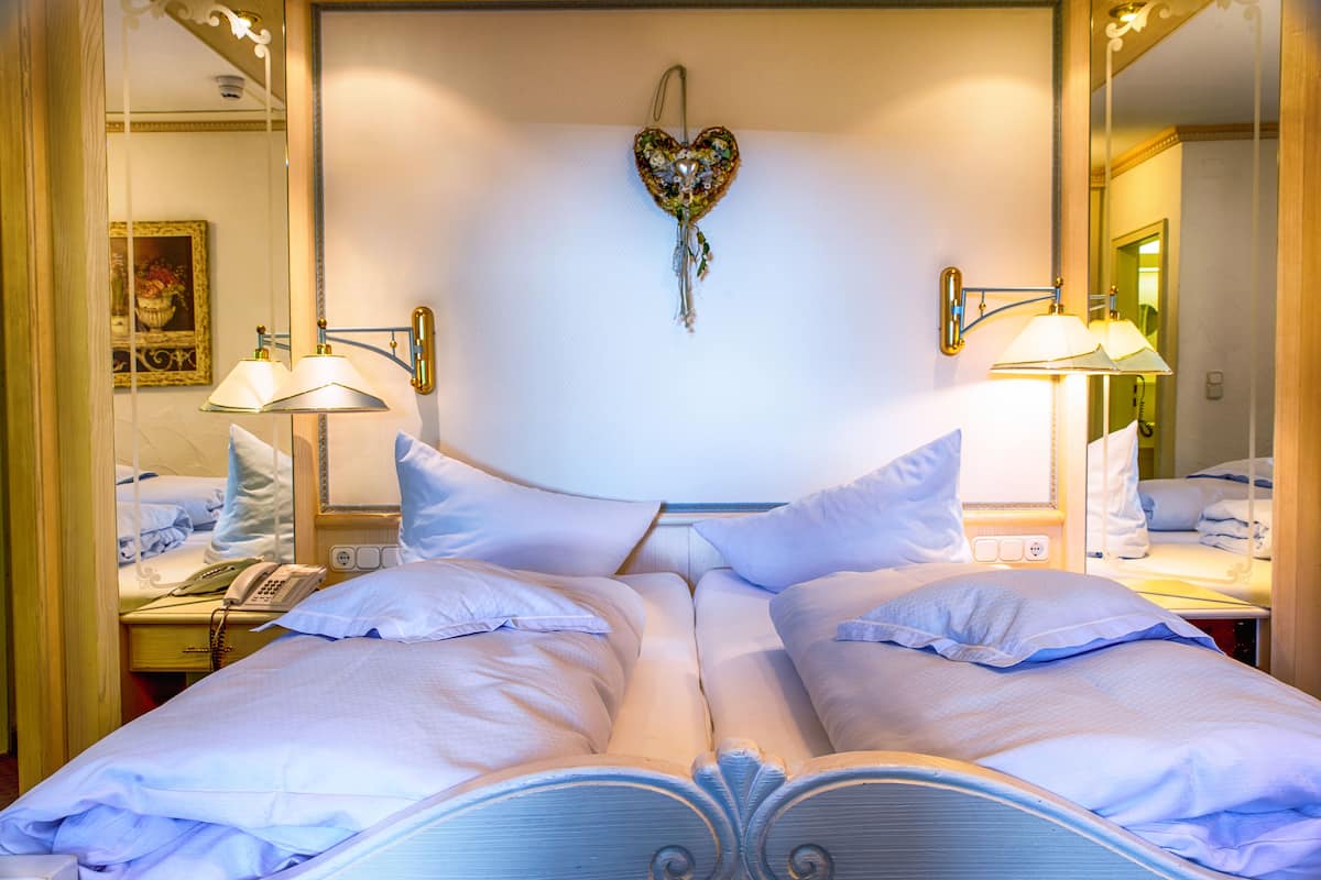 Una habitación de hotel con una cama grande, dos mesitas de noche, un espejo y una decoración con forma de corazón en la pared.