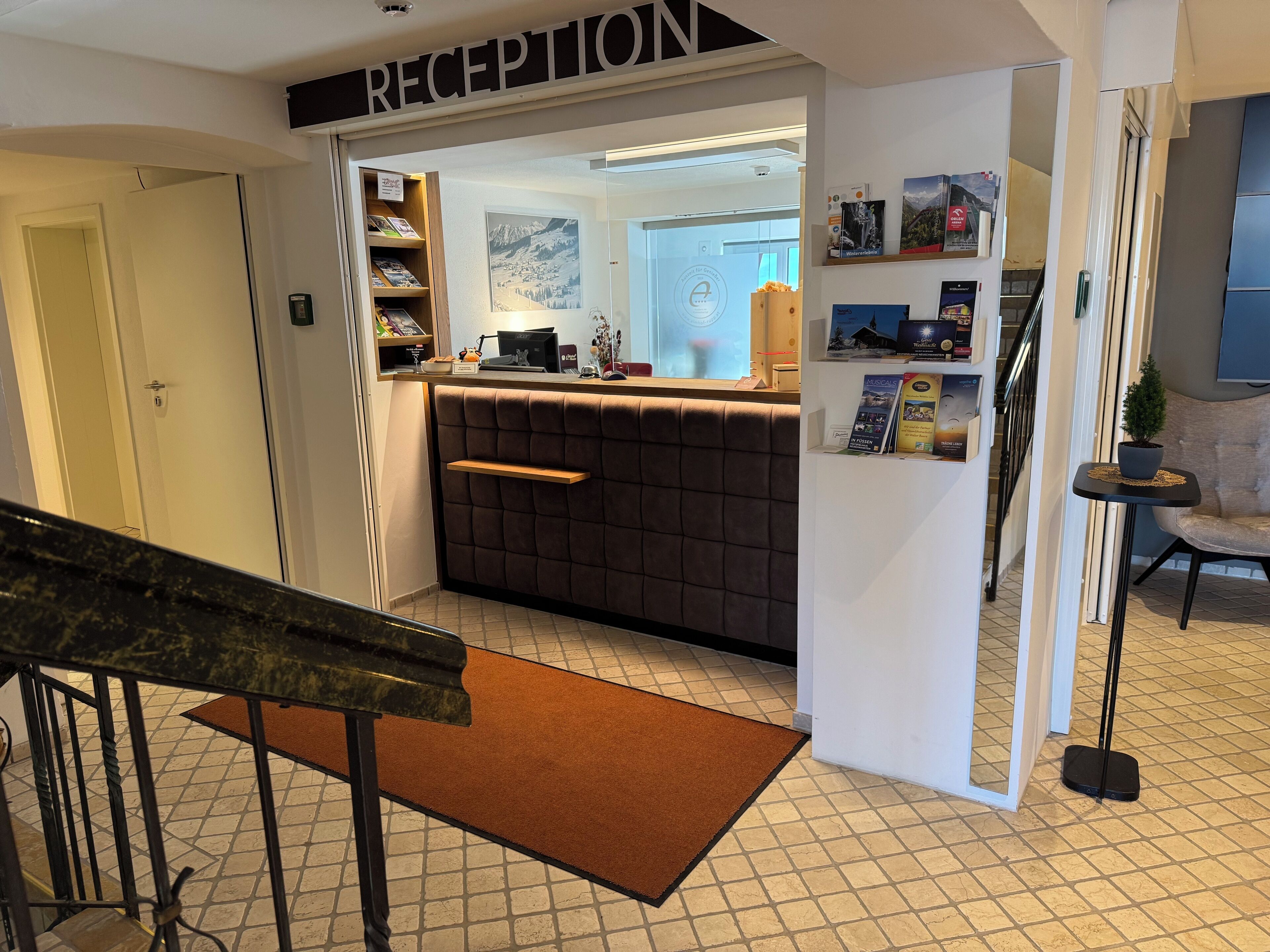 A reception area with a reception desk, a bulletin board, and a small seating area.
