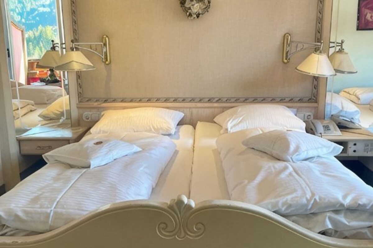 A hotel room with two beds, bedside lamps, a telephone, and a wall-mounted decoration.