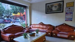A lobby with leather sofas, a marble coffee table, and a view of the street outside. - Xuanwei Yuantong Hotel (Xuanwei)