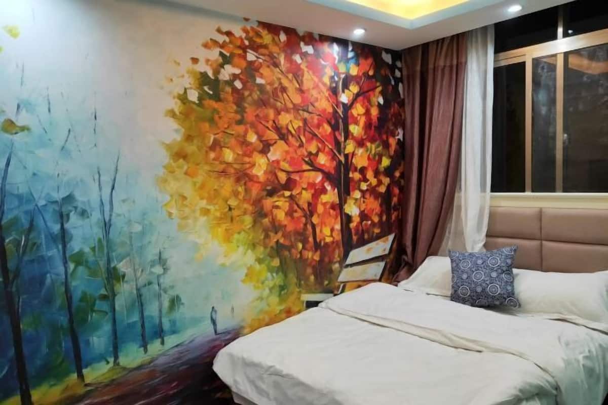 Un dormitorio con una cama, un ventanal y un mural en la pared.