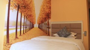A bedroom with a bed, a headboard, and a wall mural of trees. - Xuanwei Yuantong Hotel (Xuanwei)