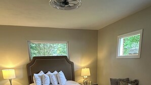 A bedroom with a large bed, two bedside tables with lamps, a chair, and a window. - Charming newly remodeled 3-bedroom house in the heart of Cleveland Tennessee (Cleveland)