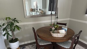 A dining area with a round table, four chairs, a potted plant, a vase with flowers, a candle holder, and a bottle of water. - Charming newly remodeled 3-bedroom house in the heart of Cleveland Tennessee (Cleveland)
