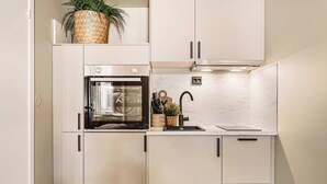 A compact kitchen with white cabinetry, a built-in oven, a sink, and a small countertop.